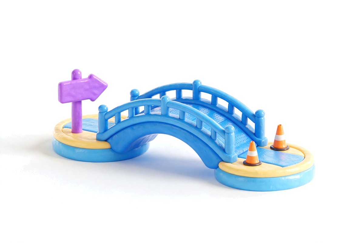Blue arched bridge between two islands with an arrow sign and a traffic cone