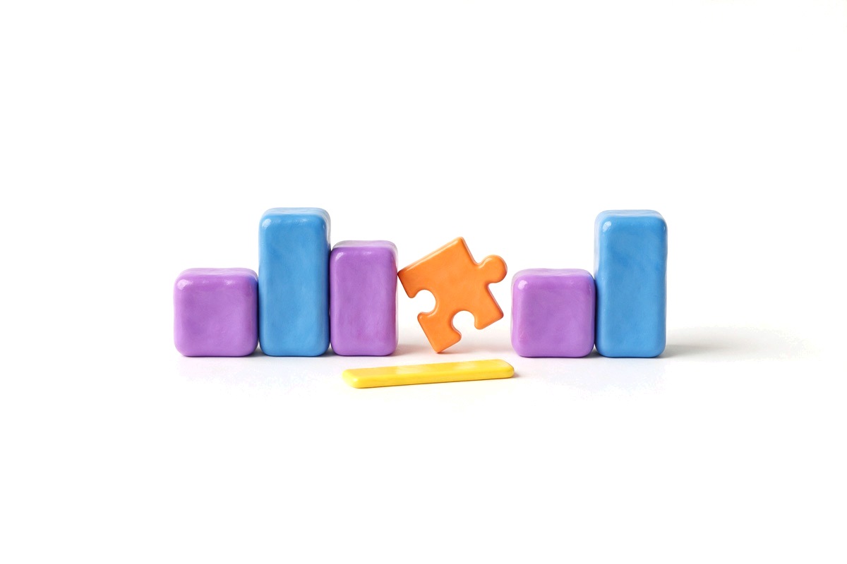 Five building blocks with a gap and an orange puzzle piece about to fit into it